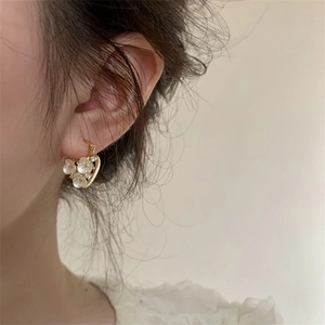 Gold plated hollow flower earrings with white pearl and diamonds worn by a model