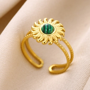Macro shot of gold sunburst ring with green malachite stone on beige fabric background