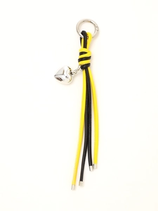 Detail of woven black and yellow leather keychain featuring a silver heart charm