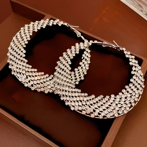 Macro shot of large silver hoop earrings featuring dense rhinestone pavé in a jewelry box