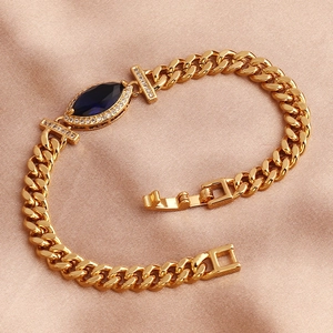 Detail of gold Cuban chain bracelet featuring a blue marquise-cut zircon on silk