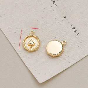 Macro detail of 15mm gold-plated circular pendant with spade motif and rope edge