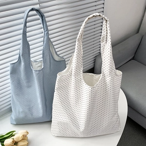 Close-up of blue and white polka dot canvas tote bags on a table with soft window light