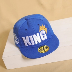 Dettaglio del cappellino hip hop blu con ricamo KING e stemma della corona dorata