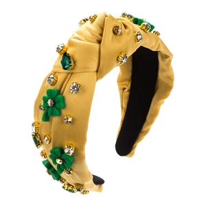 Detail of yellow satin headband featuring green clover rhinestones and metal claw settings