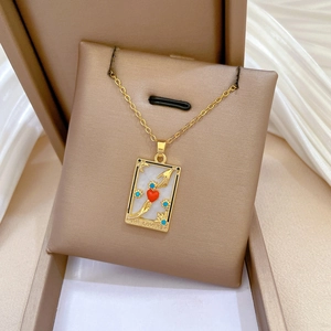Detail of tarot lovers pendant necklace with shell inlay and red heart on silk background