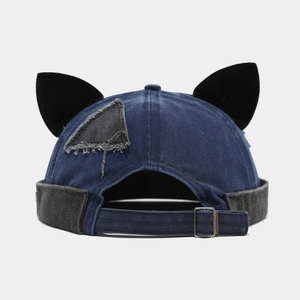 Navy denim docker hat with black cat ears and adjustable metal strap on grey background