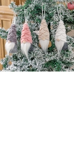 Detail of Christmas gnomes in grey pink and beige hanging on a snowy Christmas tree