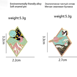 Artistic diamond-shaped enamel pins featuring snowy mountains, waves and cosmic planets