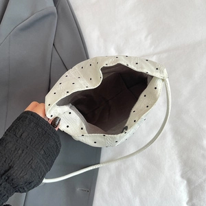 White polka dot bucket bag with interior grey lining and slim white shoulder strap