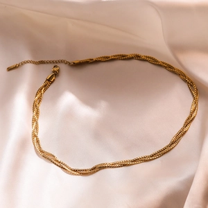 Elegant gold layered woven chain necklace with lobster clasp on silk background