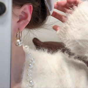 Elegant silver hook earrings featuring large round faux pearls on a stylish model