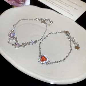 Detail of zircon Hello Kitty and red heart pendants on elegant silver charm bracelets