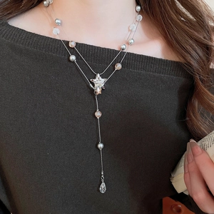 Detail of a double-layered Y-shaped necklace with star pendant and grey pearl drop