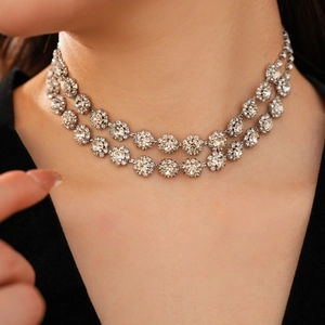 Close-up of double-layered silver floral necklace with sparkling stones on model neck