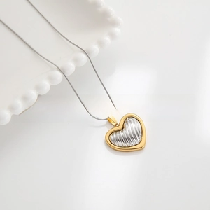 Macro shot of a two-tone heart pendant necklace with gold frame and silver texture