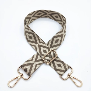 Detail showing adjustable embroidered diamond pattern bag strap with gold metal lobster clasps
