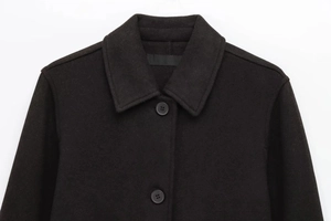 Close-up of lapel collar and single-breasted button detail on a black wool coat