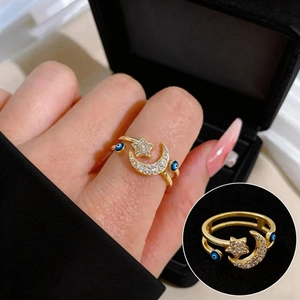 Golden celestial open ring featuring moon, stars, and blue evil eye charms with zircons