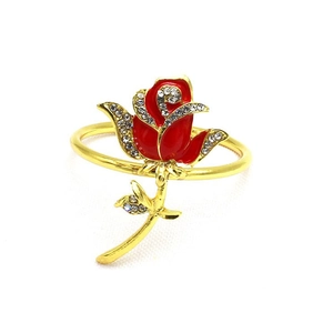 Elegant gold rose napkin ring with red petals and rhinestones on white background