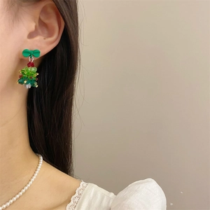 Detail of handmade beaded 3D Christmas tree earrings with a green bow and festive crystals