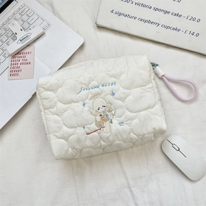 Detail of quilted beige makeup bag with cartoon angel embroidery and pink handle strap
