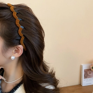 Side view of a brown wavy velvet headband worn by a model with elegant warm tones