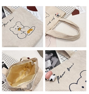 Detail view of beige corduroy tote bag showing bear embroidery and zipper closure