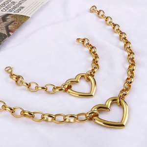 Chunky gold chain jewelry set with large heart pendants on white fabric background
