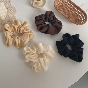 Flat lay of silk satin scrunchies in champagne, brown, cream and black colors