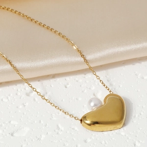 Elegant gold heart pendant necklace with pearl detail on silk background