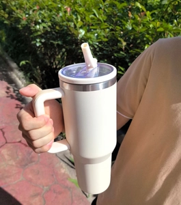 Outdoor macro of a white large insulated stainless steel tumbler with handle and straw