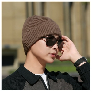 Close-up of a model wearing a brown ribbed knit winter hat with a warm fuzzy lining