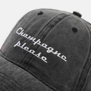 Detailed macro view of Champagne Please embroidery on washed grey cotton baseball cap