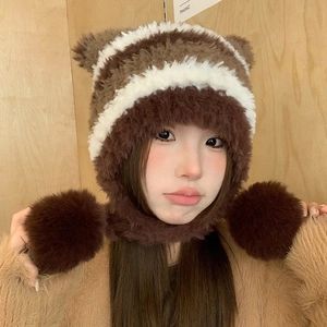 Detail of plush brown and white striped winter hat with bear ears and large fur pom-poms