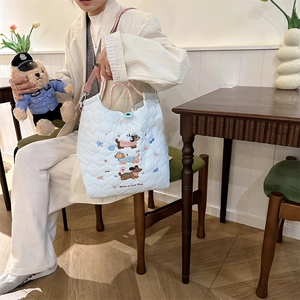 Close-up of light blue quilted tote bag featuring cute cartoon dachshund embroidery