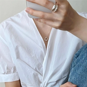 Lifestyle shot of silver geometric necklace and twisted ring on model in white shirt