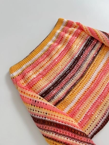 Detail des bunt gestreiften Strickstoffs mit glänzenden Pailletten auf weißem Grund