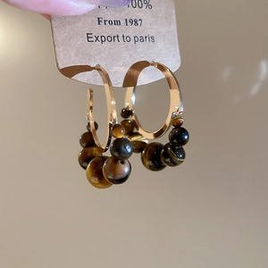 Vue détaillée de boucles d'oreilles créoles rétro avec perles œil de tigre et métal doré
