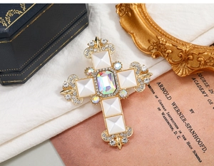 Detailed macro view of a vintage gold baroque cross brooch with crystals on a prop book