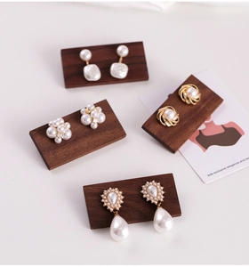 Detailed display of pearl earrings on dark walnut wood display stands for jewelry
