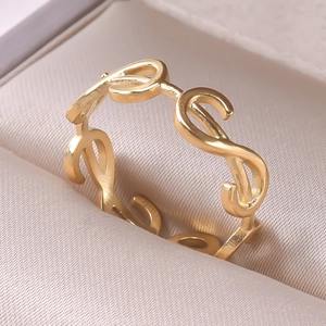 Macro detail of a gold minimalist infinity pattern stainless steel ring on a beige lining