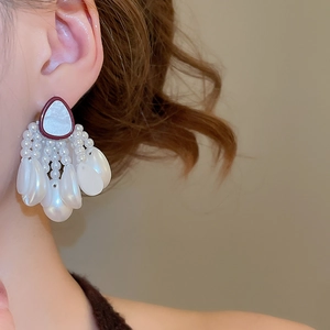 Close-up of elegant pearl tassel earrings featuring shell texture and vintage red-brown frame
