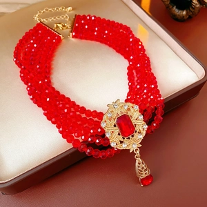 Detail of multi-layer vintage red beaded necklace with ornate gold-plated crystal pendant