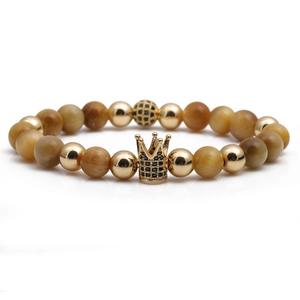 Tiger eye stone beaded bracelet with golden crown and black zircon charms on white background