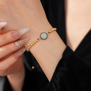 Détail du bracelet mauvais œil en zircon avec billes dorées sur fond de velours noir