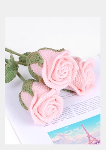 Close-up of three handmade pink crochet roses with detailed knitted textures