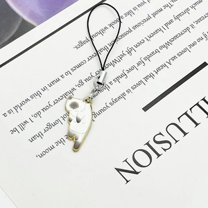 Detail of Siamese cat phone charm with enamel finish resting on a vintage book page