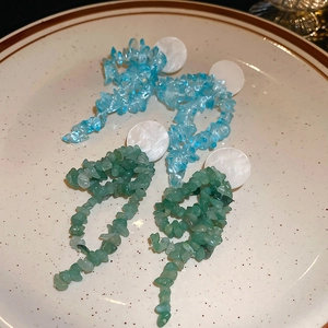 Macro detail of long tassel earrings with light blue and green irregular natural stones