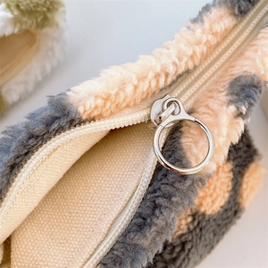 Close-up of pink leopard plush pouch with silver ring zipper and beige canvas lining